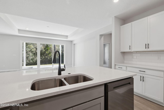 kitchen with stainless steel dishwasher, white cabinets, sink, and tasteful backsplash