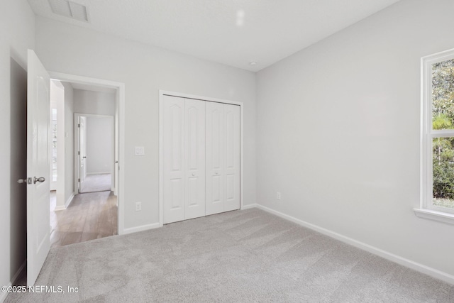 unfurnished bedroom featuring a closet and light colored carpet