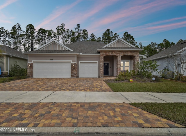 view of front of property with stone siding, decorative driveway, board and batten siding, and an attached garage