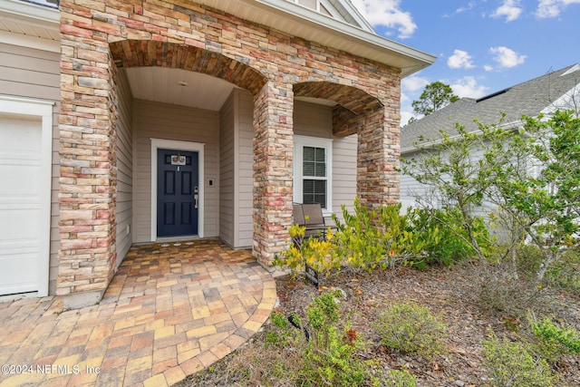 property entrance with a garage and brick siding