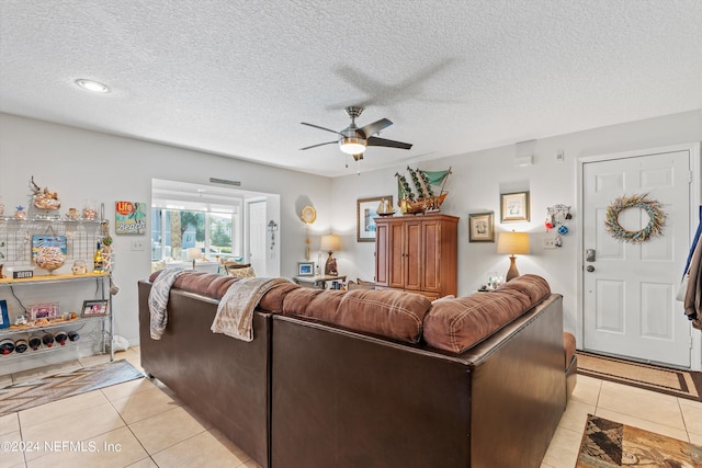 living room featuring a textured ceiling, ceiling fan, and light tile patterned floors