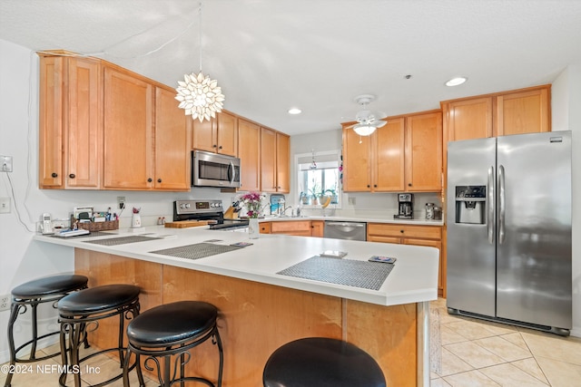 kitchen featuring a kitchen breakfast bar, appliances with stainless steel finishes, light tile patterned floors, ceiling fan, and pendant lighting