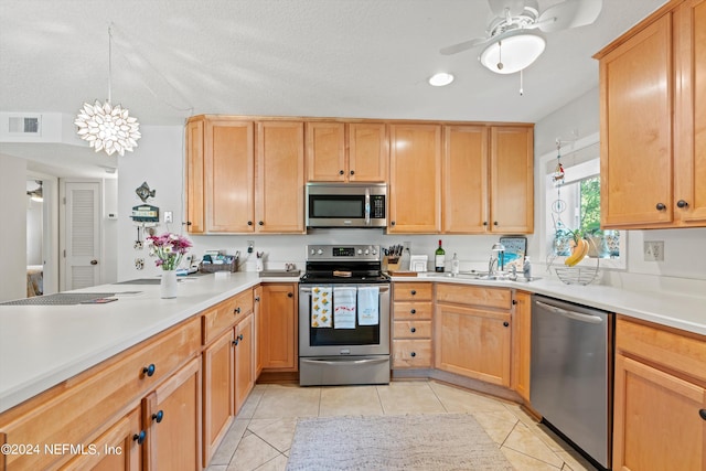 kitchen featuring stainless steel appliances, light tile patterned floors, pendant lighting, a textured ceiling, and ceiling fan with notable chandelier