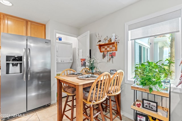 tiled dining room featuring stacked washer / dryer