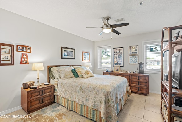 bedroom featuring ceiling fan, multiple windows, a textured ceiling, and light tile patterned floors