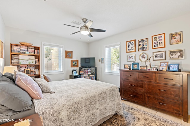 tiled bedroom featuring ceiling fan and multiple windows