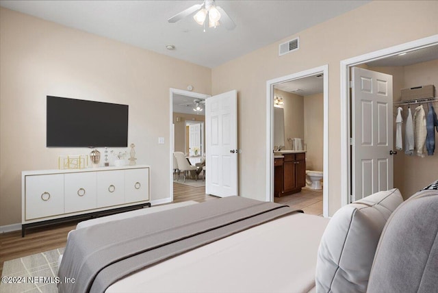 bedroom with a closet, hardwood / wood-style flooring, ceiling fan, ensuite bath, and a walk in closet