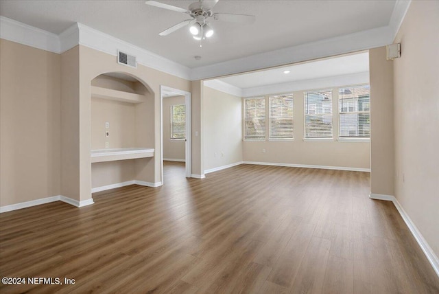 spare room featuring ornamental molding, built in shelves, hardwood / wood-style flooring, and ceiling fan