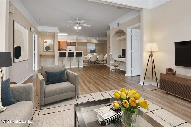 living room with ornamental molding, ceiling fan, and light wood-type flooring