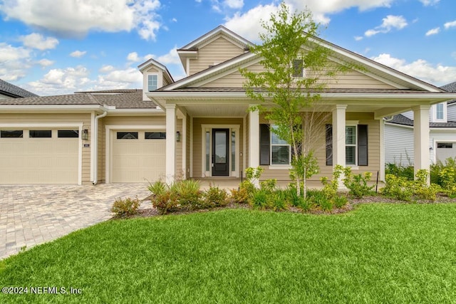 view of front of house with a garage, covered porch, and a front yard