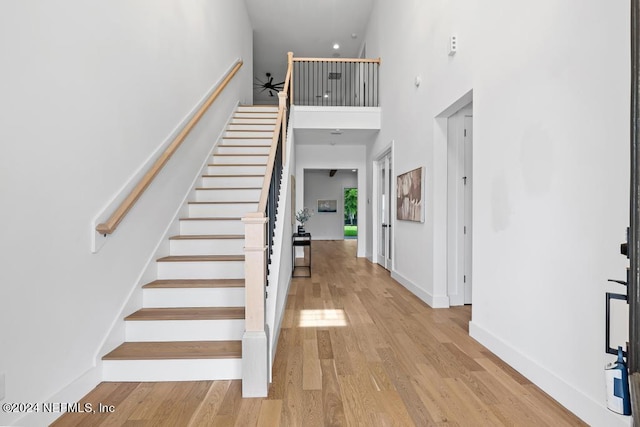 stairway featuring light hardwood / wood-style floors and a towering ceiling