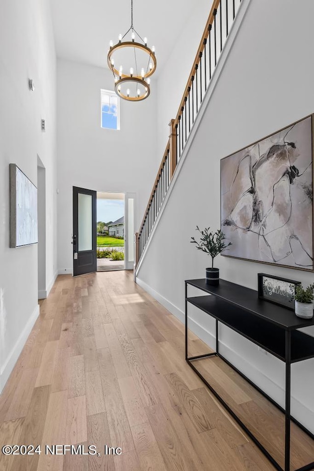 foyer with a high ceiling, a chandelier, and light hardwood / wood-style flooring