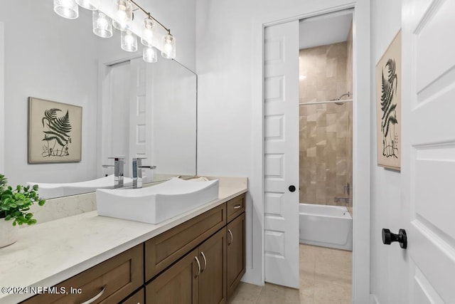 bathroom with tiled shower / bath combo, vanity, and tile patterned flooring