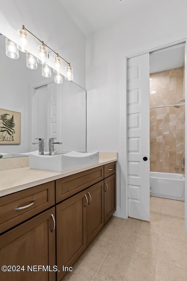 bathroom with tiled shower / bath combo, vanity, and tile patterned flooring