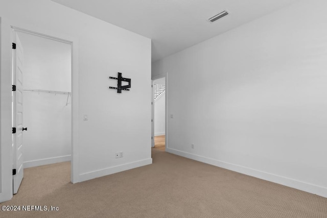 unfurnished bedroom with light carpet and a closet