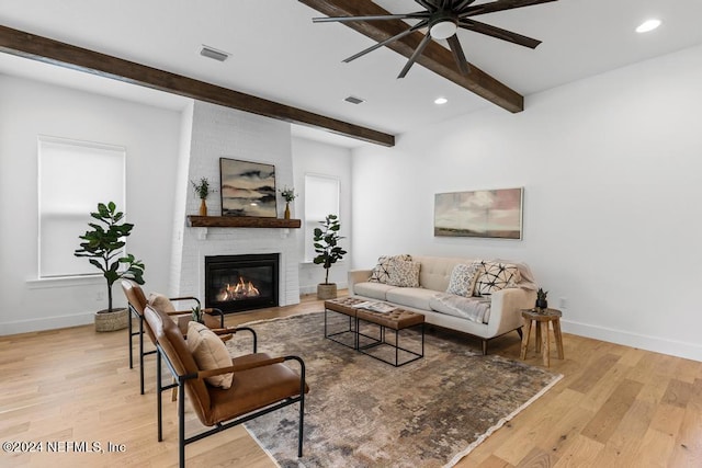 living room featuring light hardwood / wood-style flooring, a brick fireplace, and beam ceiling