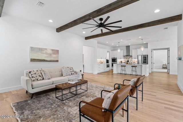 living room with beamed ceiling, light hardwood / wood-style flooring, and ceiling fan