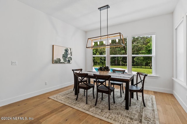 dining space with light hardwood / wood-style floors and a chandelier