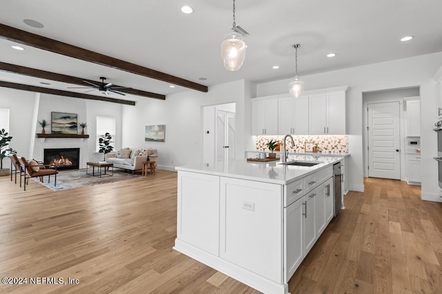 kitchen with light hardwood / wood-style floors, sink, decorative light fixtures, and white cabinets