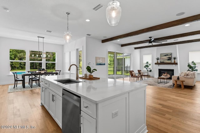 kitchen featuring stainless steel dishwasher, hanging light fixtures, sink, a center island with sink, and light hardwood / wood-style floors