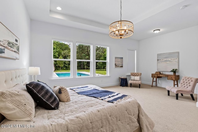 carpeted bedroom with an inviting chandelier and a raised ceiling