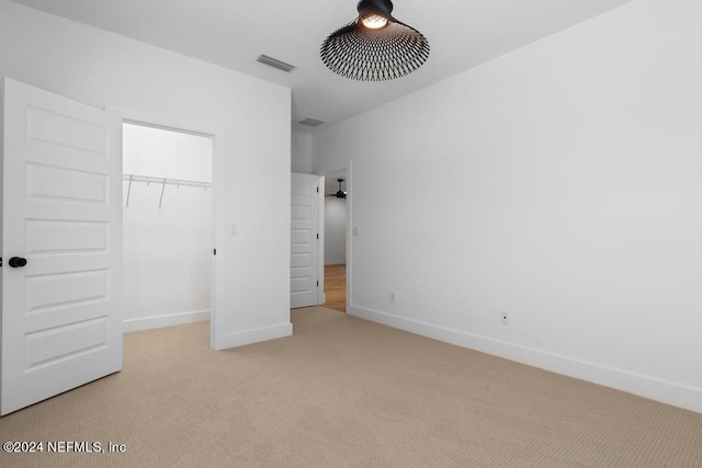 unfurnished bedroom featuring light carpet and a closet