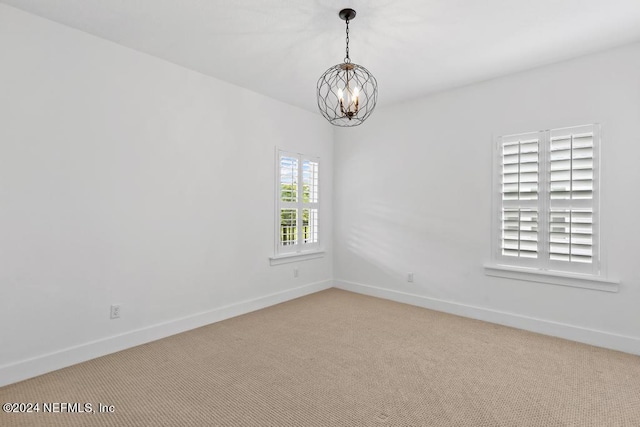 unfurnished room featuring a chandelier and carpet floors