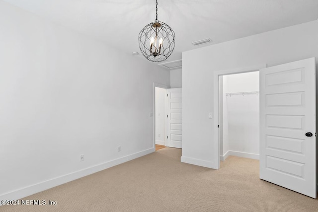 unfurnished bedroom with light colored carpet, a closet, and an inviting chandelier