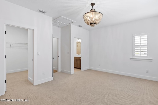 unfurnished bedroom with a spacious closet, a closet, connected bathroom, a chandelier, and light carpet