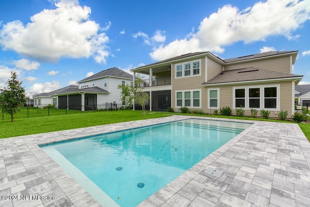 rear view of property featuring a yard and a fenced in pool