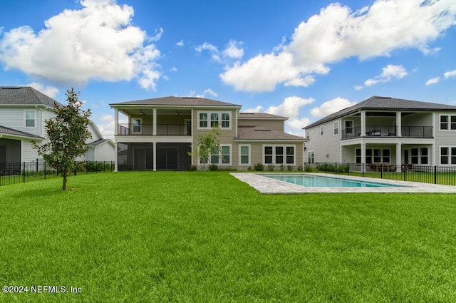 back of house featuring a balcony, a sunroom, a fenced in pool, and a lawn