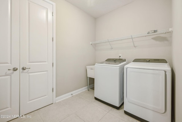 washroom with washing machine and clothes dryer and light tile patterned floors