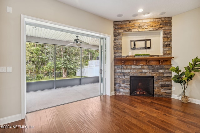 unfurnished living room featuring ceiling fan, a stone fireplace, and hardwood / wood-style flooring