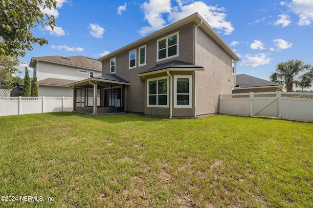 rear view of property featuring a lawn and a sunroom