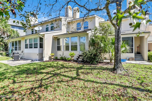 back of property with a yard and a patio area