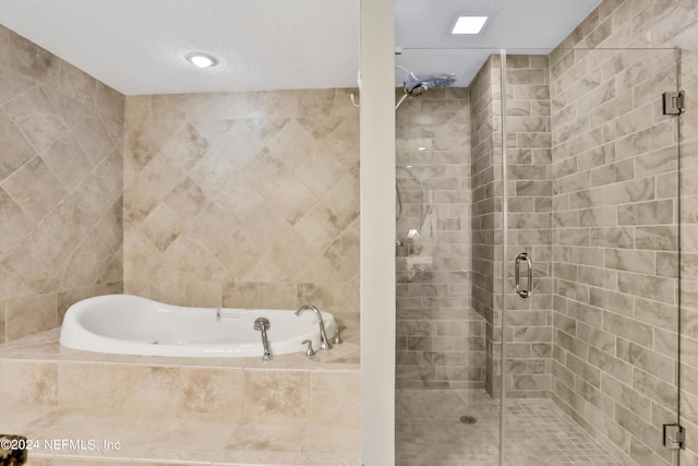 bathroom featuring shower with separate bathtub and tile walls