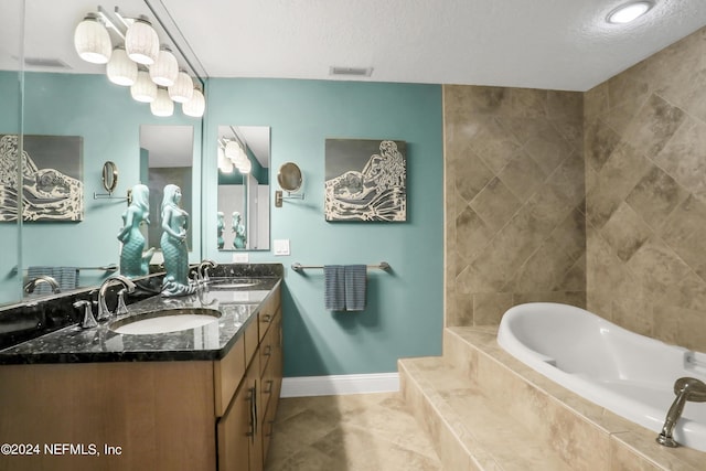 bathroom with vanity, a textured ceiling, and tiled bath