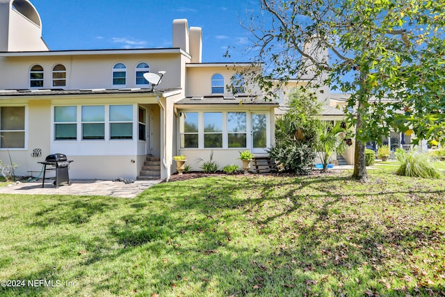 back of house featuring a lawn and a patio