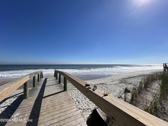 view of dock with a water view and a beach view