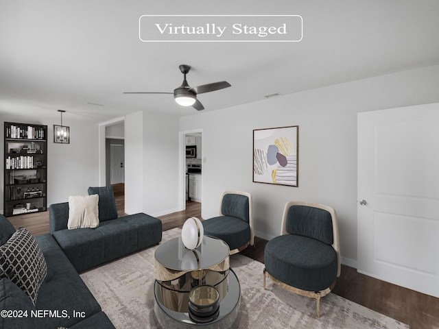 living room with ceiling fan with notable chandelier and hardwood / wood-style flooring