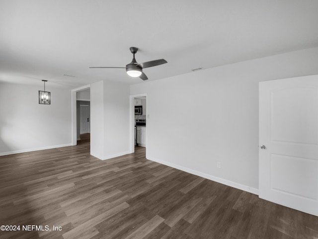 unfurnished room featuring dark hardwood / wood-style flooring and ceiling fan with notable chandelier