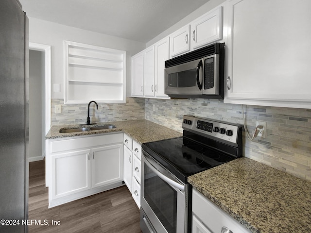 kitchen with appliances with stainless steel finishes, white cabinetry, stone counters, and sink