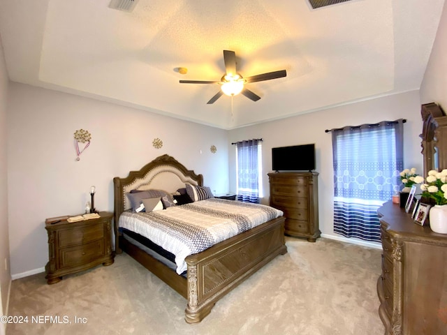 bedroom featuring a raised ceiling, ceiling fan, and light colored carpet