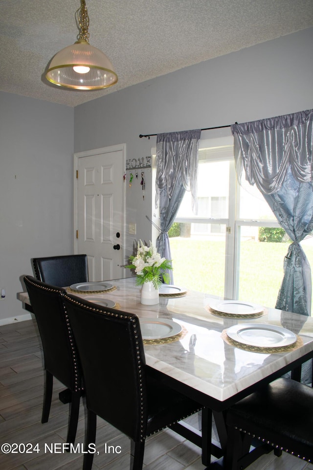 dining area with wood-type flooring and a textured ceiling