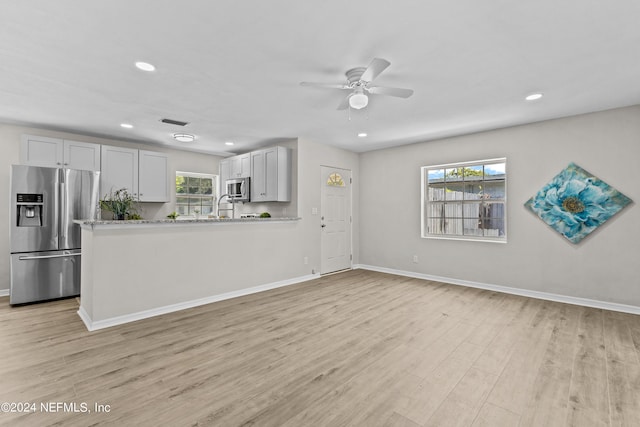 kitchen featuring kitchen peninsula, light hardwood / wood-style flooring, ceiling fan, appliances with stainless steel finishes, and white cabinetry