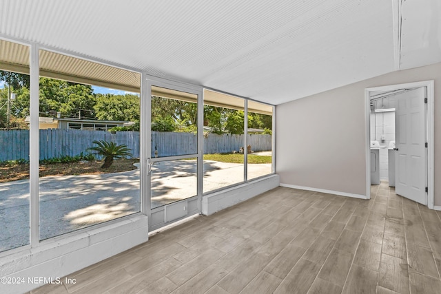 unfurnished sunroom featuring washer / clothes dryer and vaulted ceiling