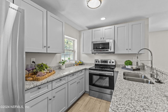 kitchen with light stone counters, sink, and stainless steel appliances