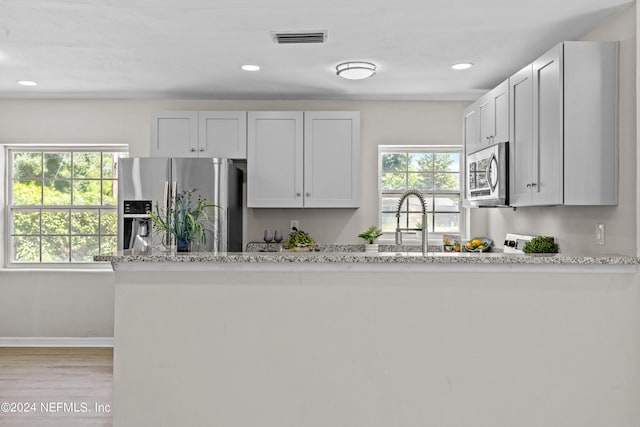 kitchen with light stone countertops, white cabinets, and stainless steel appliances