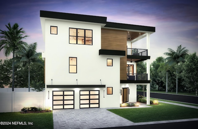 contemporary home featuring a ceiling fan, a balcony, fence, decorative driveway, and stucco siding