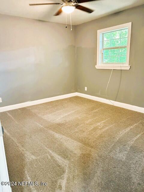 carpeted spare room featuring ceiling fan